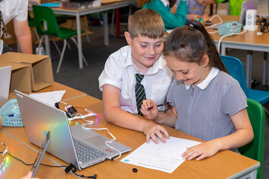 A boy and girl at school in a computing workshop.